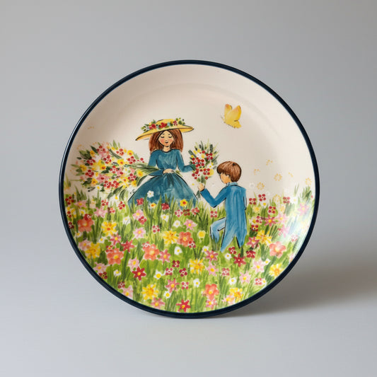 Decorative plate with a colorful illustration of two people in a floral field on a red woven surface.