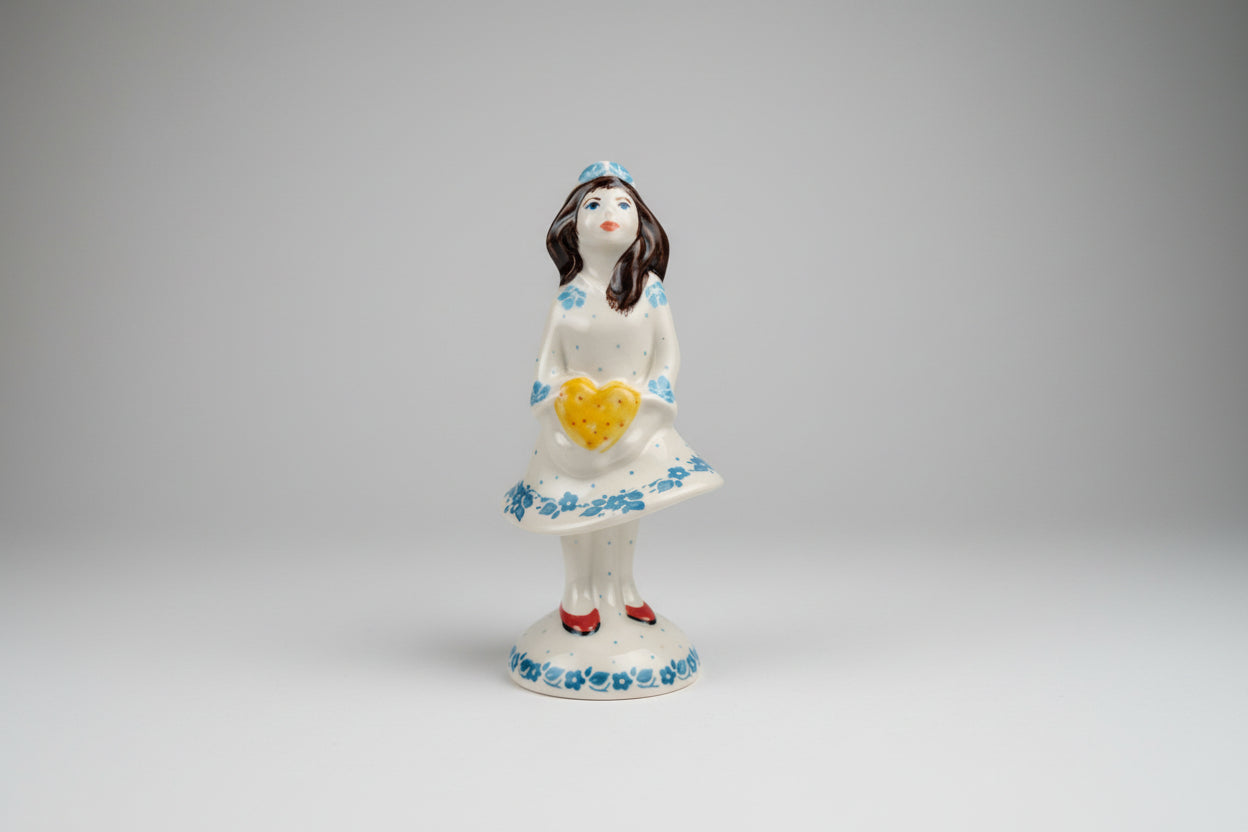 Decorative figurine of a woman holding a heart on a doily