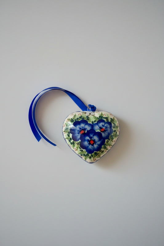 Heart-shaped decorative item with floral design on a crocheted surface