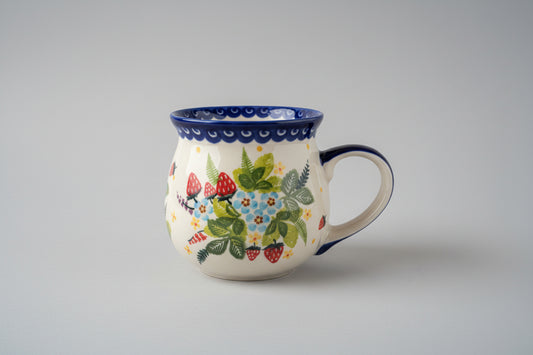 Ceramic mug with floral and strawberry design on a textured surface