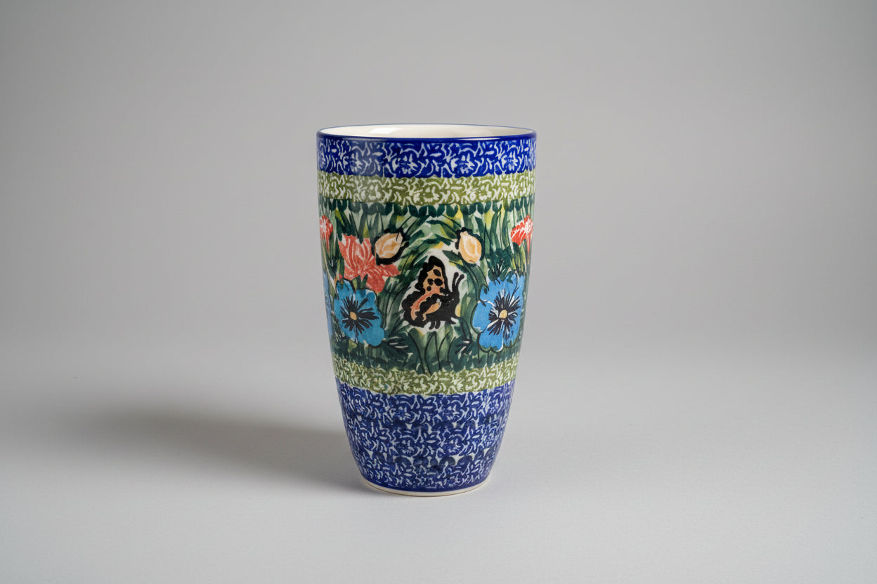 Decorative ceramic vase with floral and butterfly design on a lace tablecloth.