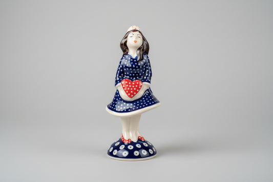 Ceramic figurine of a woman with a heart design on a lace tablecloth